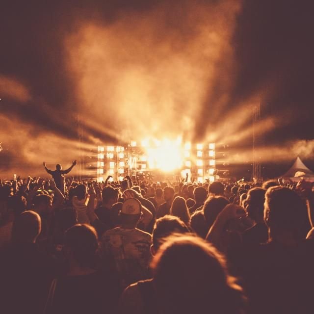 Multidão diante de um palco iluminado por luz âmbar